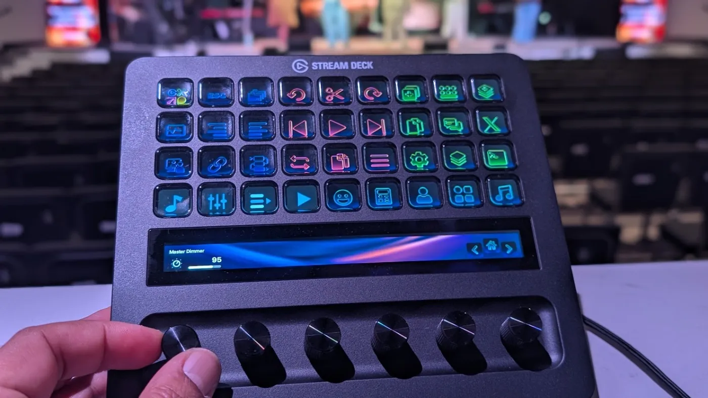 A hand turning a Stream Deck + dial while the touchscreen above it shows a live level readout
